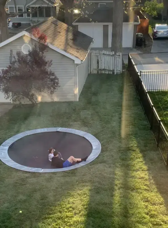 children laying on round gray trampoline
