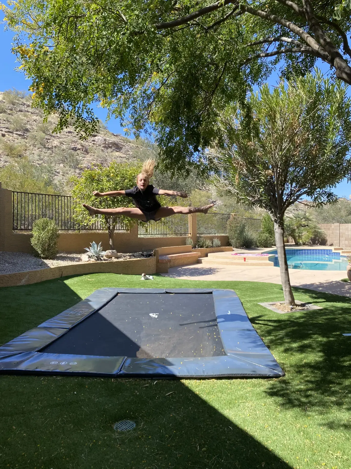 child doing tricks on a black inground trampoline