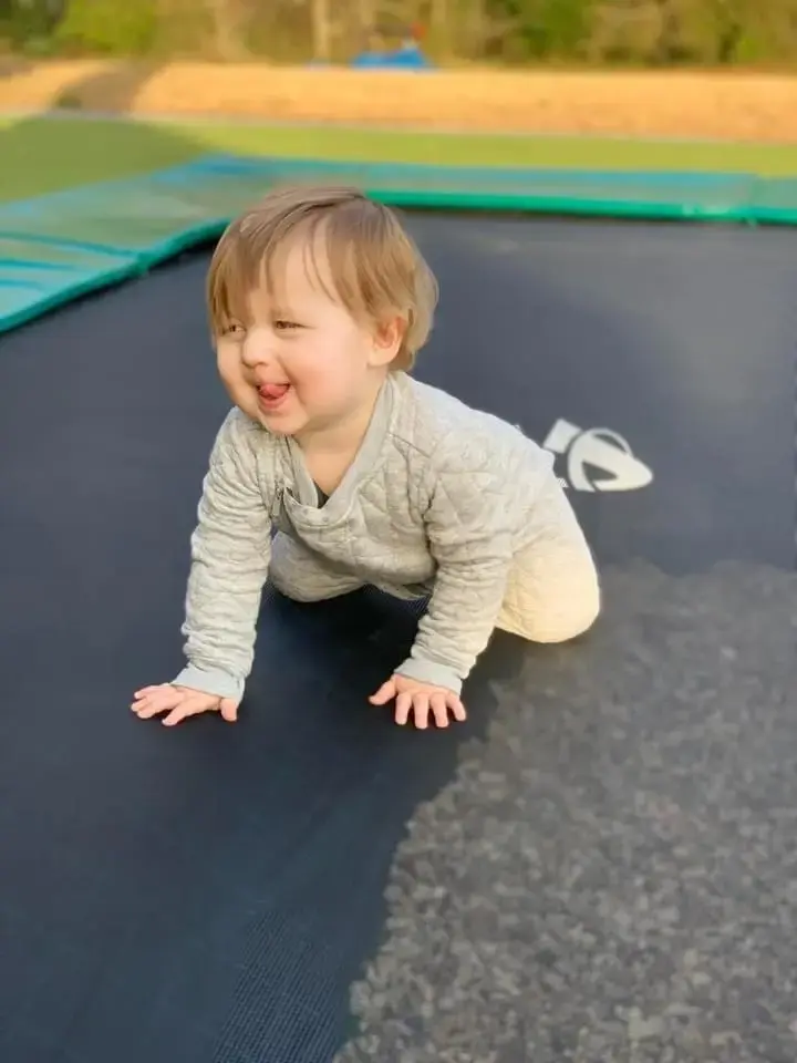 toddler playing on a green inground trampoline