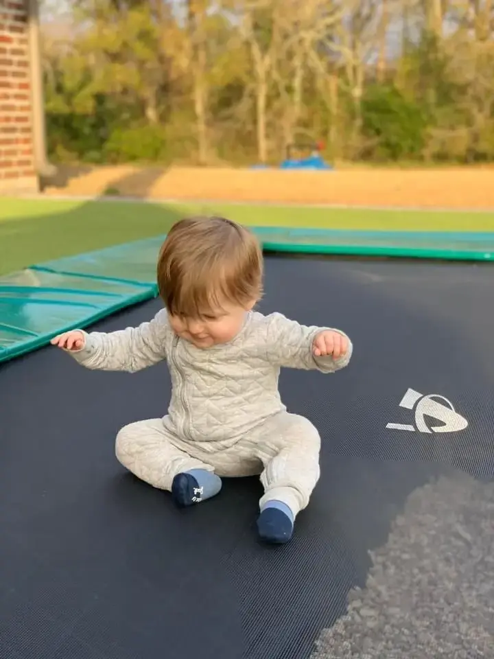 toddler playing on a green inground trampoline